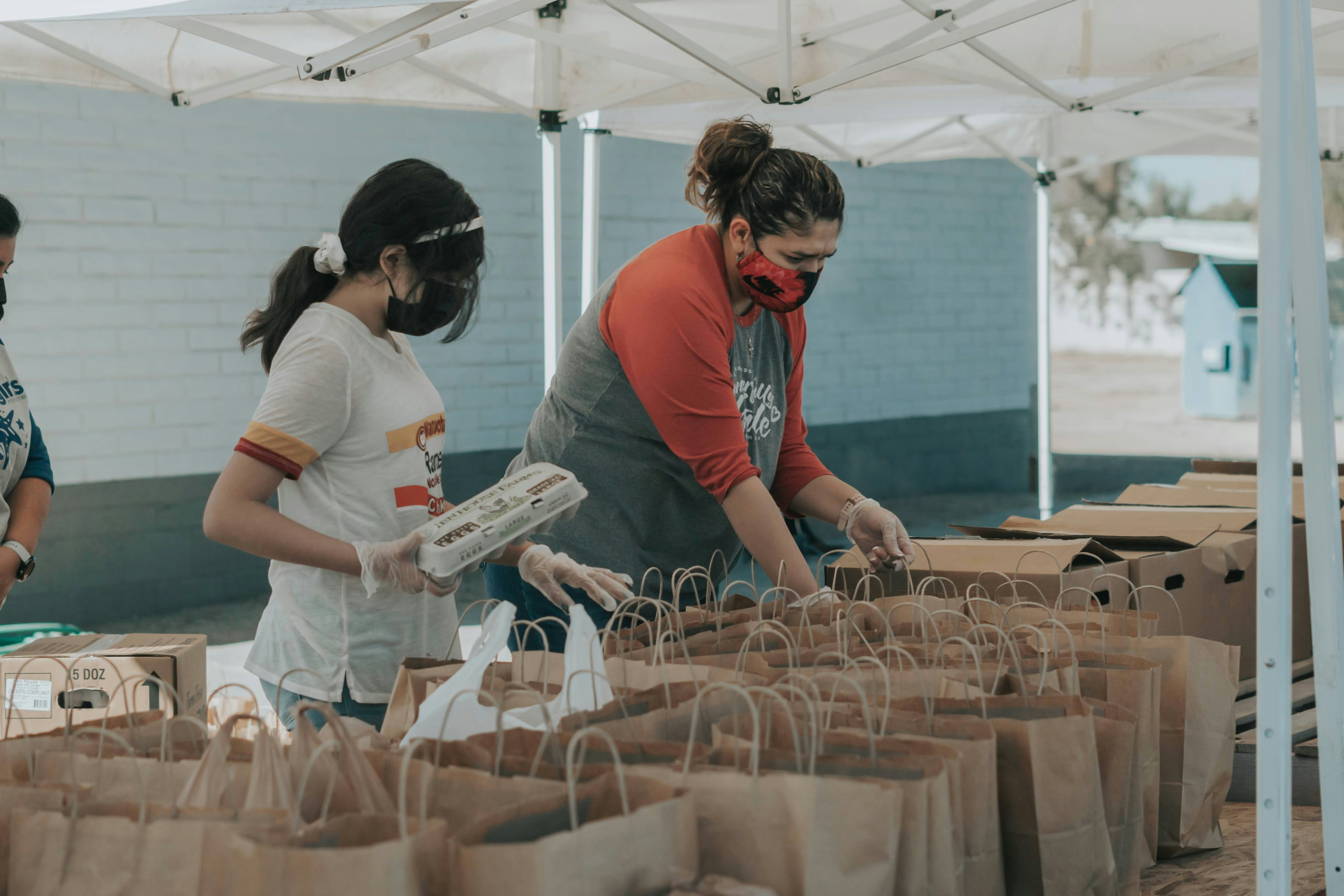people with paper bags of food under tents